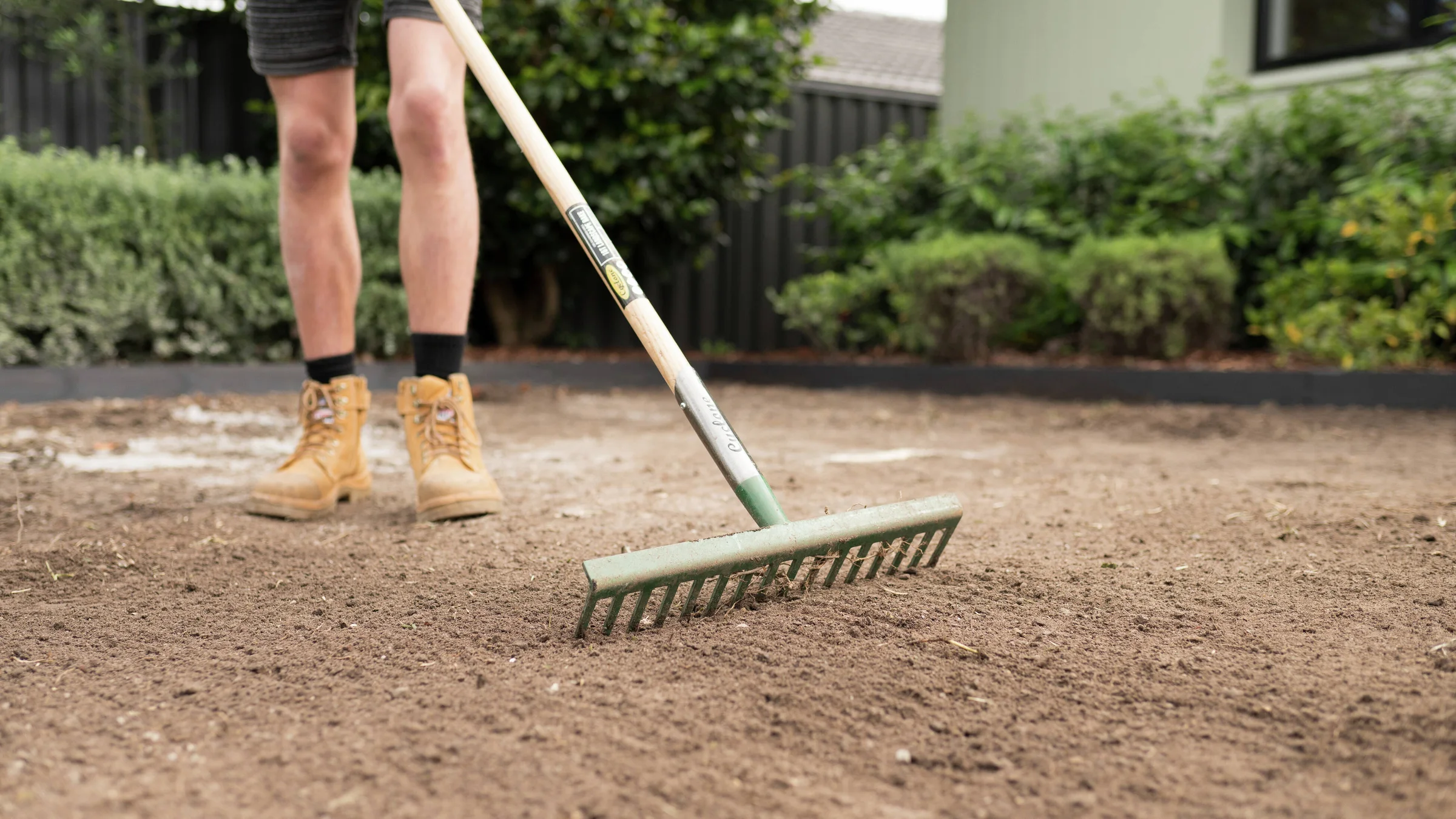Soil being levelled with a landscape rake before turf installation